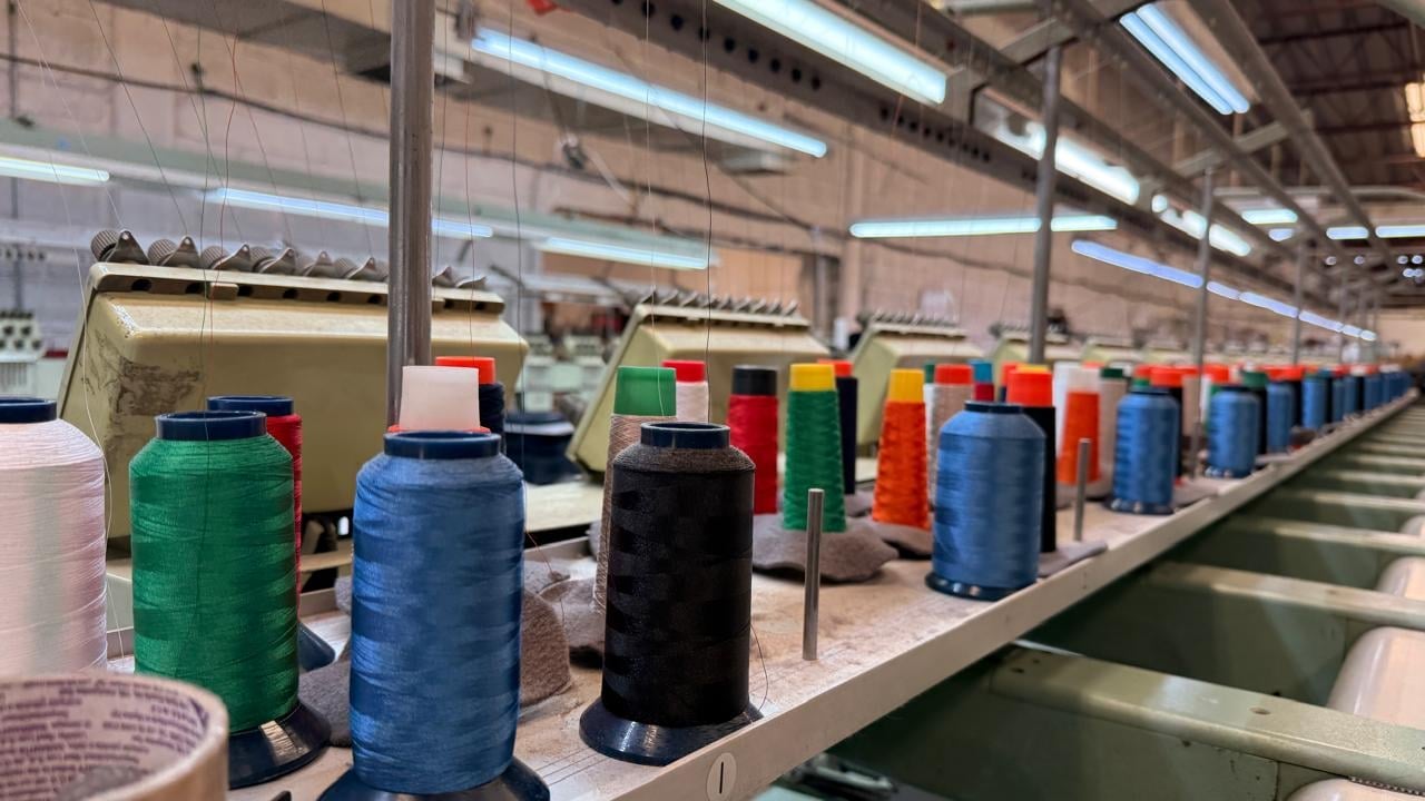 Industrial textile factory with large colorful thread spools arranged in rows on conveyor belts